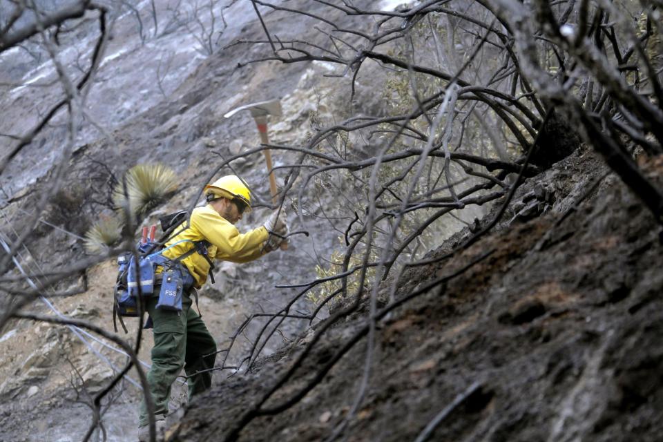 Firefighter Romero Mercado checks for hotspots in the Angeles National Forest Wednesday Sept. 5, 2012 near Los Angeles. Fire crews are getting help from rain in battling a 3,800-acre fire in the San Gabriel Mountains northeast of Los Angeles. (AP Photo/Nick Ut)