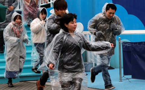 Participants run during an anti-missile evacuation drill at the Tokyo Dome City amusement park in Tokyo - Credit: Reuters