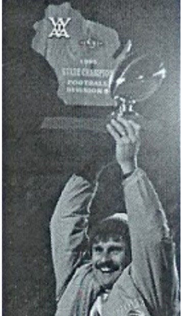 New Berlin Eisenhower coach Jeff Setz hoists the 1995 WIAA state football championship trophy after defeating Ashland, 7-6.