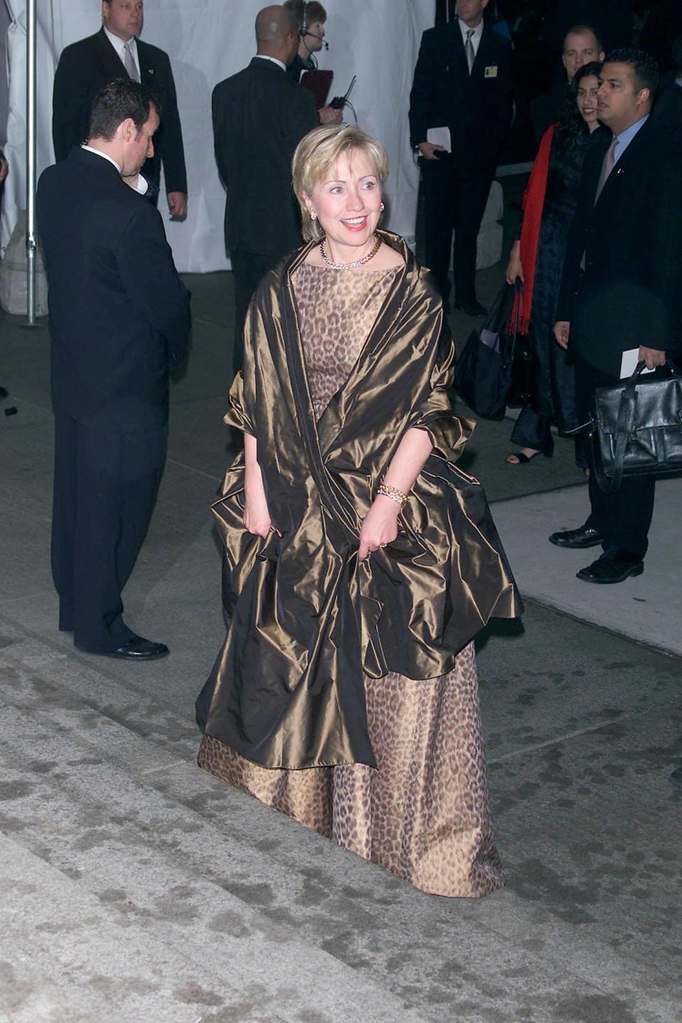 Hillary Clinton, dressed in a cheetah-print gown with a bronze shawl draped around her shoulders, enters the Met Gala in 2001.