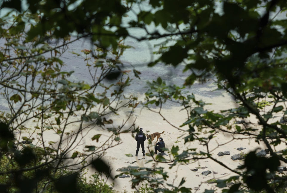 In this Wednesday, June 9, 2021 file photo, police with a dog patrol on the beach near the Carbis Bay Hotel in Carbis Bay, St. Ives, Cornwall, England. Towering steel fences and masses of police have transformed the Cornish seaside as leaders of the Group of Seven wealthy democracies descent for a summit near St. Ives in Cornwall, a popular holiday destination. A huge frigate dominates the coastline, armed soldiers guard the main sites and some 5,000 extra police officers have been deployed to the area. (AP Photo/Jon Super, File)