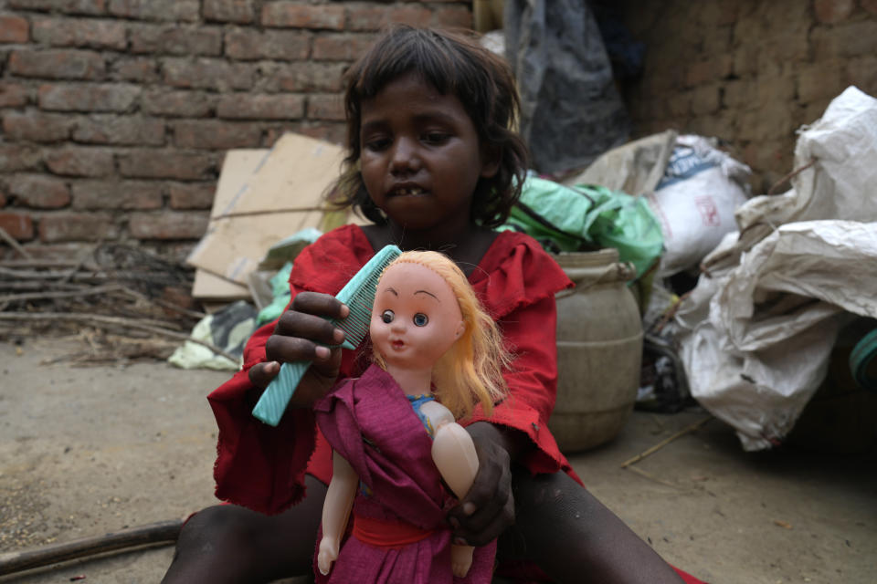 A girl from an impoverished family plays with a doll outside her hut on the outskirts of Patna, in the Indian state of Bihar, on May 11, 2024. (AP Photo/Manish Swarup)