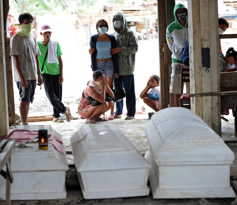 Residents stand next to coffins of deceased relatives who died during flash floods caused by Typhoon Bopha in New Bataan in Compostela Valley province on December 8. While the powerful typhoon had weakened to a tropical storm, it was still causing downpours in the north