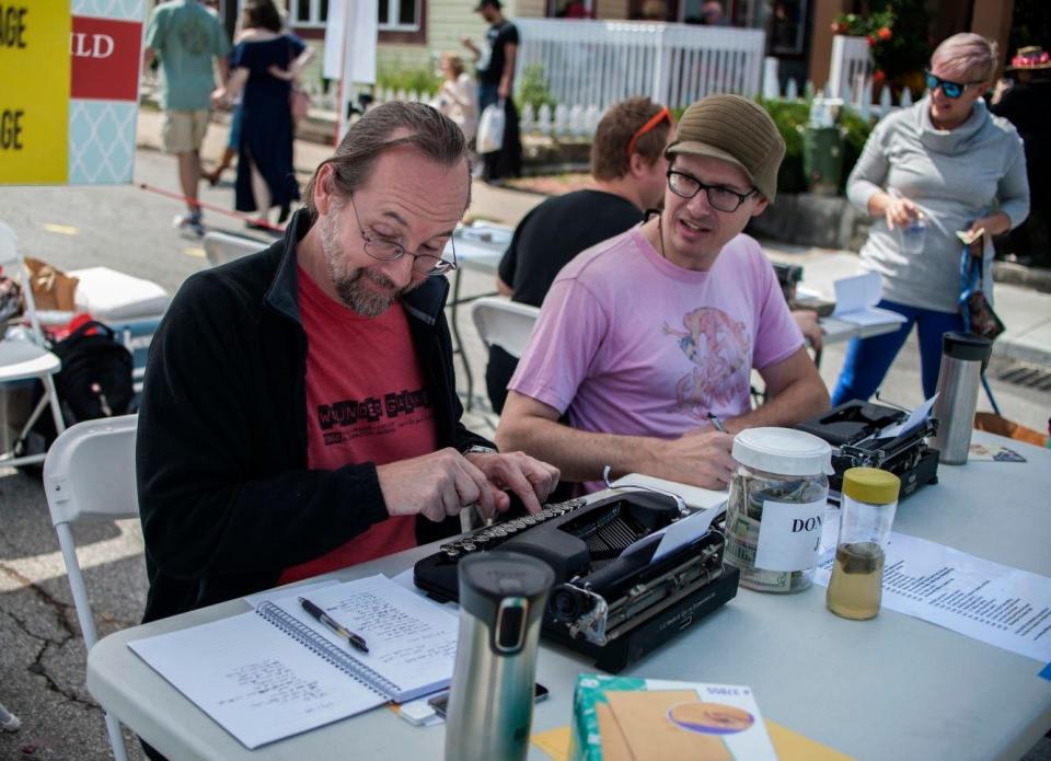 Tony Brewer, chairman of Writers Guild of Bloomington, left, and Blaine Carrell converse while writing poetry for visitors to Poetry On Demand during the Fourth Street Festival of the Arts & Crafts in 2017. Brewer said the guild has had a table at the annual downtown event since 2011 and views it as an important chance for people to see writers in action.