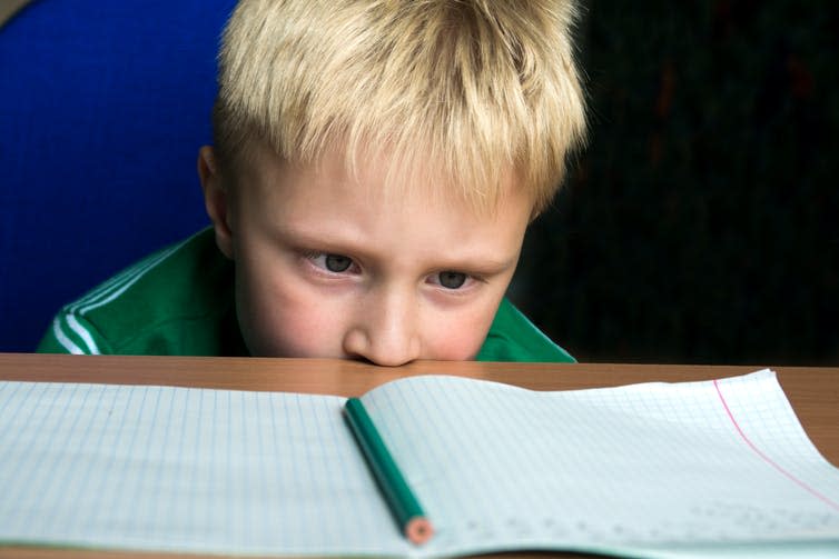 Boy looking apprehensively at homework