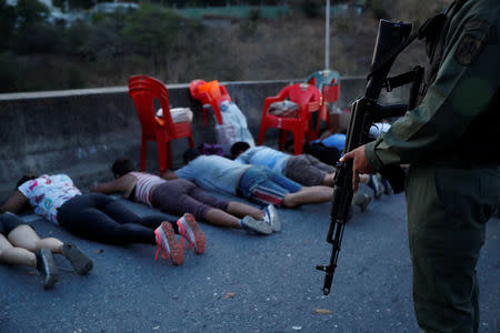 A security force member stands next to detainees on a street after looting during an ongoing blackout in Caracas, Venezuela March 10, 2019. REUTERS/Carlos Garcia Rawlins