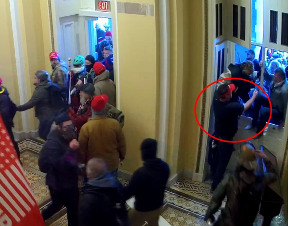 Schubert (circled in red) helping his parents climb through a broken window into the Capitol. (DOJ)