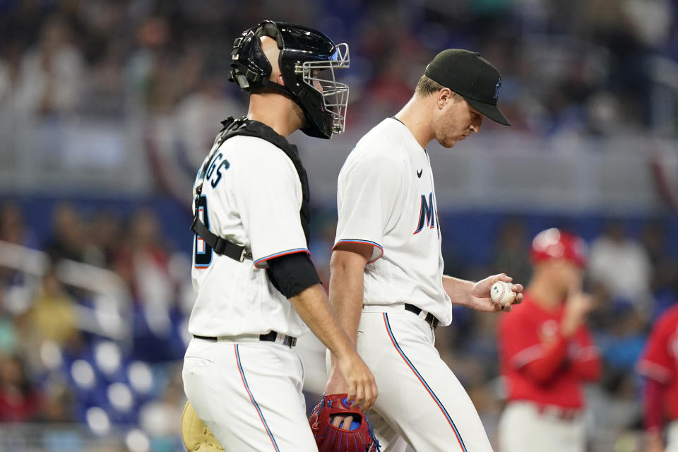 Miami Marlins catcher Jacob Stallings, left, talks with starting pitcher Trevor Rogers, right, during the first inning of a baseball game against the Philadelphia Phillies, Saturday, April 16, 2022, in Miami. (AP Photo/Lynne Sladky)