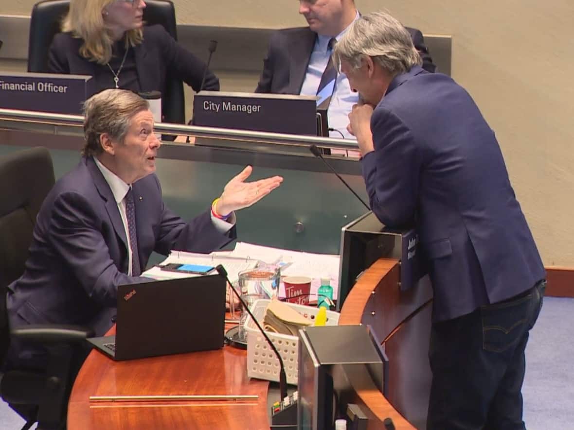 Mayor John Tory talks with Coun. Gord Perks during a debate about studying new taxes and fees for the city. The pair, who often disagree on policy, both voted in favour of the request of city staff to investigate possible new 'revenue tools' for the city. (Alexis Raymond/CBC - image credit)