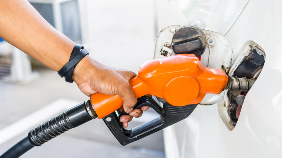 Hand holding an orange bio-fuel pump to a vehicle