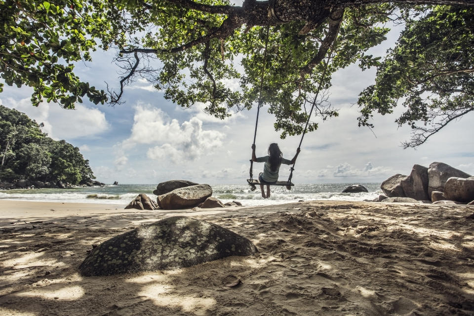 A woman swings on a beach in Khao Lak, Thailand