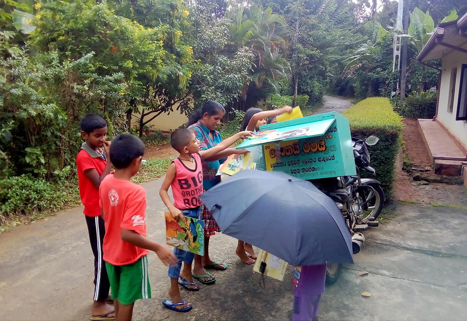 Children look to borrow books from a mobile library run on a motorbike by Mahinda Dasanayaka, in a village in Kegalle district, about 85 kilometers (53 miles) northeast of Sri Lanka's capital, Colombo, Sept. 5, 2020. Having witnessed the hardships faced by children in rural areas whose villages have no library facilities, Dasanayaka got the idea for his library on wheels called “Book and Me." Dasanayaka, 32, works as a child protection officer for the government. On his off days, mostly during weekends, he rides his motorbike, which is fixed with a steel box to hold books, to rural villages and distributes the reading material to children free of charge. (AP Photo)