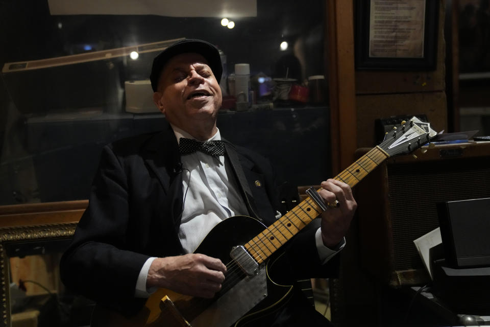 Guitarist and singer Deacon John Moore strums a guitar at his home in New Orleans, Wednesday, May 3, 2023. Moore has been a regular performer at the New Orleans Jazz & Heritage Festival since it began in 1970, and is playing the festival again this year. (AP Photo/Gerald Herbert)