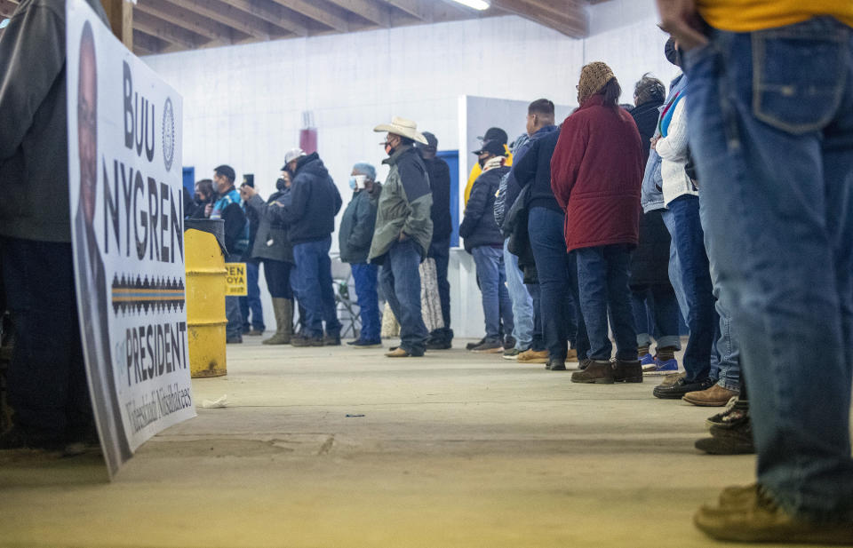 People stand in line for food at the Nygren Montoya camp on Tuesday, Nov. 8 2022, at the Navajo Nation Fairgrounds in Window Rock, Ariz. Navajo voters are deciding Tuesday who they want to be their next president, a position that wields influence nationally because of the tribe's hefty population and the size of it reservation in the U.S. Southwest. (AP Photo/William C. Weaver IV)