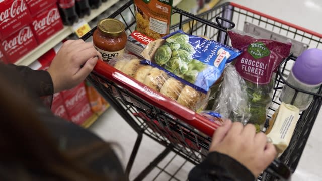 A food shopper pushes a cart of groceries at a supermarket