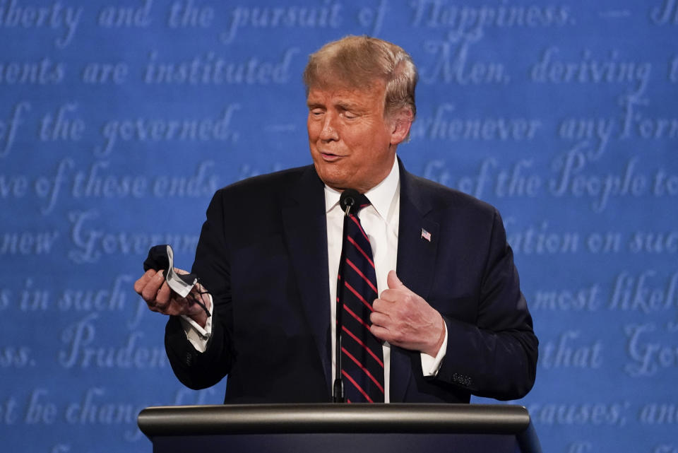 President Donald Trump holds out his face mask during the first presidential debate at Case Western University and Cleveland Clinic, in Cleveland, Ohio, Sept. 29, 2020. (AP Photo/Julio Cortez)