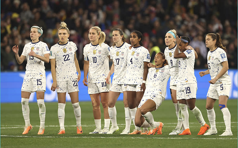 Members of the U.S. women's soccer team stand in a line to watch their penalty shootout against Sweden
