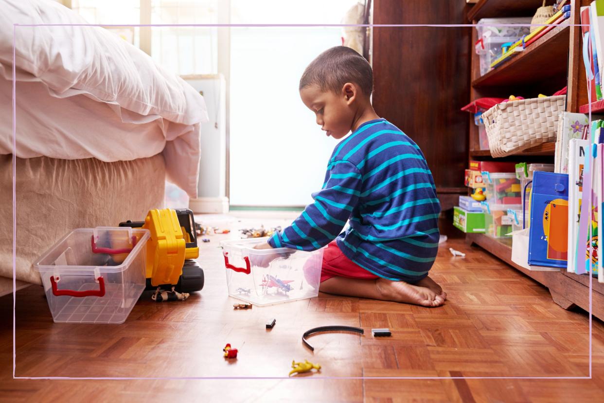  A young boy sat on the floor while putting toys into boxes. 