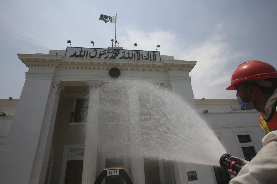 A volunteer sprays disinfectant outside a provincial assembly building to help contain the spread of the coronavirus, in Peshawar, Pakistan, Thursday, June 18, 2020. (AP Photo/Muhammad Sajjad)