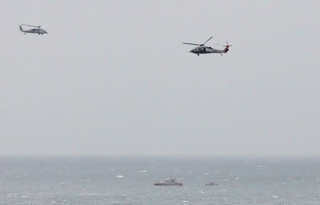 FILE PHOTO: A Iranian Revolutionary Guard boat is seen near the U.S. aircraft carrier USS George H. W. Bush in the Strait of Hormuz as U.S. Navy helicopters hover nearby on March 21, 2017. REUTERS/Hamad I Mohammed/File Photo