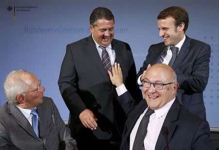 German Economy and Finance Ministers Sigmar Gabriel and Wolfgang Schaeuble (L) and their French counterparts Michel Sapin (2nd R) and Emmanuel Macron (R) smiles after a news conference at the finance ministry in Berlin October 20, 2014. REUTERS/Thomas Peter