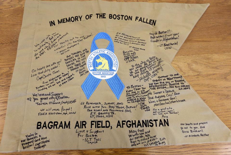 In this March 26, 2014 photo, a banner which features messages of support and condolence from members of the armed services stationed at Bagram Air Field, in Afghanistan, that was part of the original memorial to bombing victims near the finish of the 2013 Boston Marathon, rests on a table at the city archives in Boston. Thousands of items from the original memorial are going on display at the Boston Public Library in April 2014 to mark the anniversary of the attacks. (AP Photo/Steven Senne)