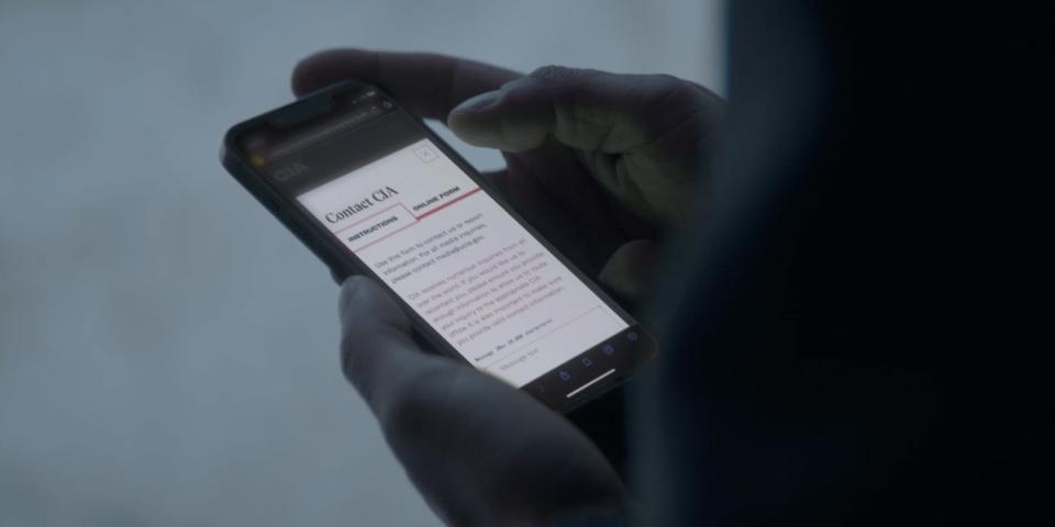 A screenshot from a CIA recruitment video aimed at Russians posted online on May 15, 2023, showing a view of hands holding a smartphone, on which the CIA website is displayed.