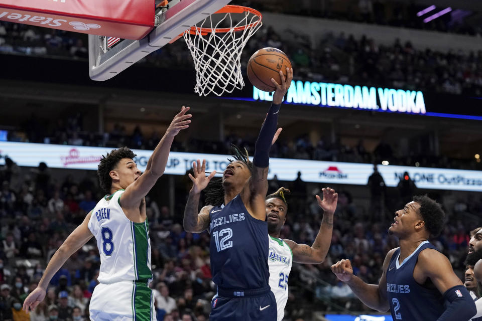 Dallas Mavericks guard Josh Green (8) and Reggie Bullock (25) defend as Memphis Grizzlies guard Ja Morant (12) shoots in front of center Xavier Tillman (2) in the first half of an NBA basketball game in Dallas, Sunday, Jan. 23, 2022. (AP Photo/Tony Gutierrez)