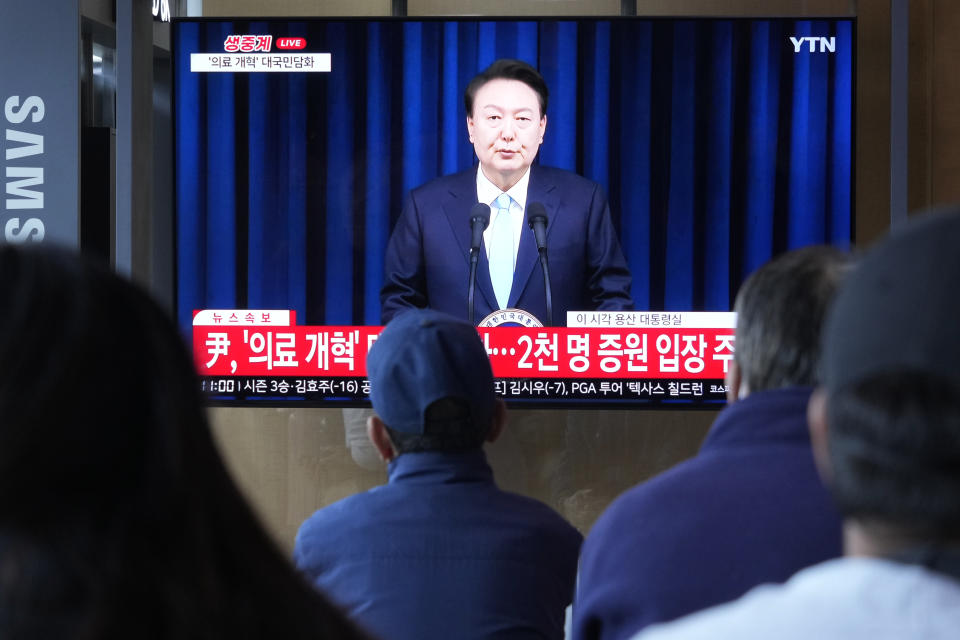 People watch a TV screen showing the live broadcast of South Korean President Yoon Suk Yeol’s addressing the nation at the Seoul Railway Station in Seoul, South Korea, Monday, April 1, 2024. President Yoon vowed Monday not to back down in the face of vehement protests by doctors seeking to spike his plan to drastically increase medical school admissions, as he called their walkouts “an illegal collective action” that poses "a grave threat to our society.” (AP Photo/Ahn Young-joon)