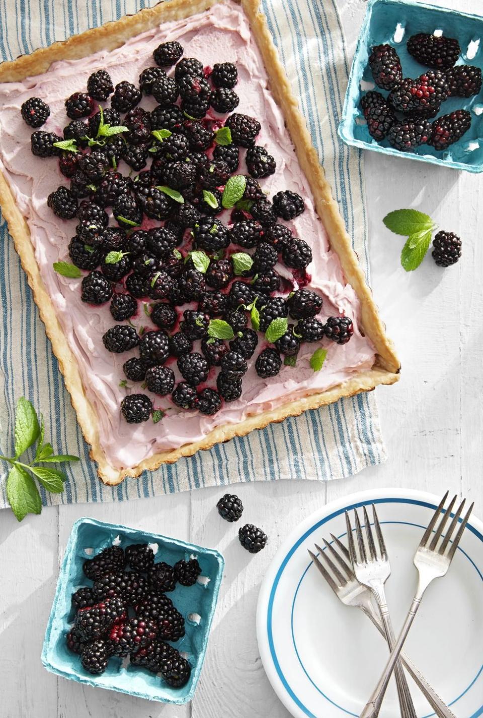blackberry tart on a dish towel with more blackberries surrounding