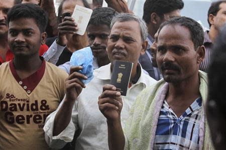 Foreign workers hold their passports as they gather outside a labour office, after missing a deadline to correct their visa status, in Riyadh November 4, 2013. REUTERS/Faisal Al Nasser