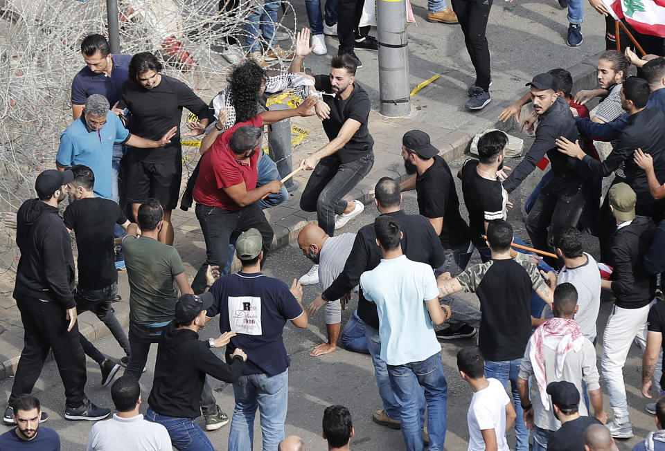Anti-government protesters and Hezbollah supporters clash during a protest near the government palace, in downtown Beirut, Lebanon, Friday, Oct. 25, 2019. Hundreds of Lebanese protesters set up tents, blocking traffic in main thoroughfares and sleeping in public squares on Friday to enforce a civil disobedience campaign and keep up the pressure on the government to step down. (AP Photo/Hussein Malla)