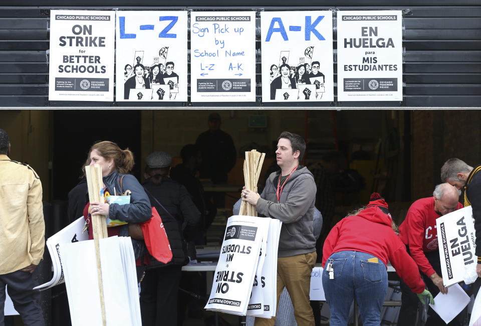 Chicago Teachers Union members pick up picket signs ahead of the pending strike at the CTU Center, Wednesday, Oct. 16, 2019, in Chicago. Chicago parents and community groups are scrambling to prepare for a massive teachers' strike set to begin Thursday, prompting the city to preemptively cancel classes in the nation's third-largest school district. (John J. Kim/Chicago Tribune via AP)