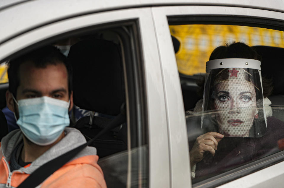 Marisol Aro, wearing a face shield with an image of Wonder Woman, looks out from a car window, amid the new coronavirus pandemic in Santiago, Chile, Saturday, June 27, 2020. Aro's husband bought her the face shield who has since been infected with the new coronavirus and is now intubated in an intensive care unit. (AP Photo/Esteban Felix)