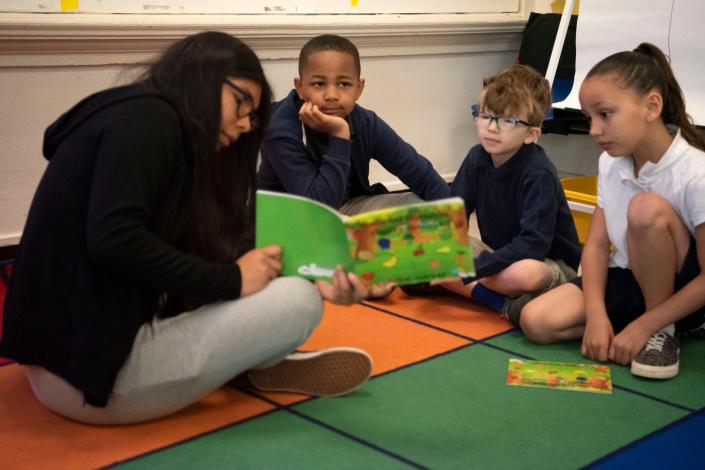 Battle Creek Central student Yadira Romero reads the story she wrote to second graders Mariono Mccray, Hunter Snyder and Kennidey Williams at Fremont International Academy on Thursday, May 19, 2022.