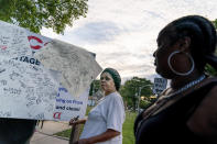 Snovia Gosa signs a message on a memorial board for a friend who was killed by gun violence as residents from neighboring blocks attend a 'peace picnic' in the Auburn Gresham neighborhood in Chicago, Saturday, Aug. 22, 2020. Last year, 1,149 guns were recovered from the 6th police district, which includes Auburn Gresham, about 10 percent of the haul for the entire city. As of the end of September, the district had recorded 59 homicides this year, nearly 60 percent higher than the same period last year. (AP Photo/David Goldman)