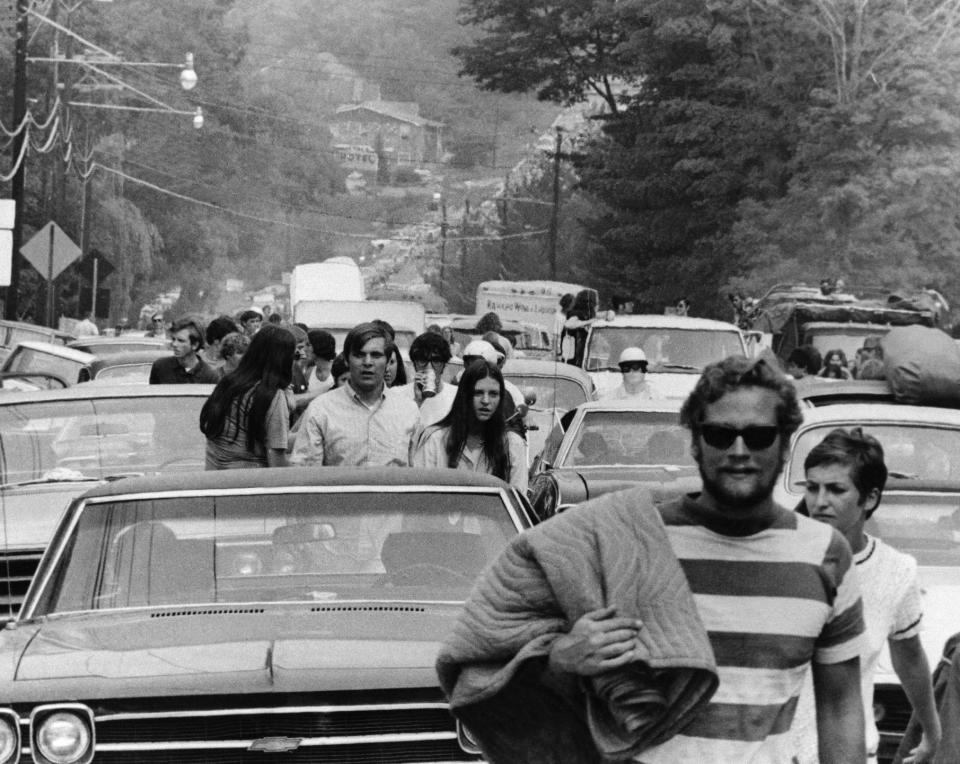 FILE - In this Aug. 15, 1969 file photo, concert goers abandon their trucks, cars and buses as thousands try to reach the Woodstock Music and Art Festival at White Lake in Bethel, N.Y. Although Arlo Guthrie famously announced from the festival stage that "The New York State Thruway is closed, man," that wasn't exactly the case. Police closed at least one thruway exit east of the festival to stem the source of a blockbuster traffic jam around the site. The New York Daily News reported on Aug. 16 that cars were being delayed by as much as eight hours between New York City and the concert site - a distance of less than 100 miles. (AP Photo)