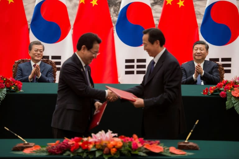 South Korean President Moon Jae-In (L) and Chinese President Xi Jinping (R) applaud during a signing ceremony at the Great Hall of the People in Beijing on December 14, 2017