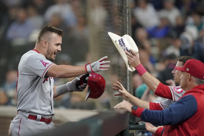 Los Angeles Angels' Mike Trout reaches for a cowboy hat at the dugout after he hit a two-run home run.