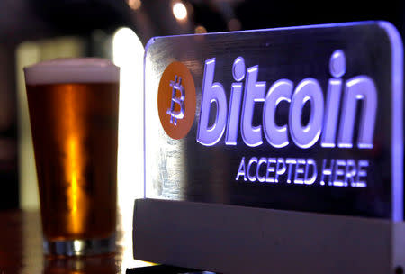 FILE PHOTO: A beer sits next to a Bitcoin sign on display at a bar in central Sydney, Australia, September 29, 2015. REUTERS/David Gray/File Photo