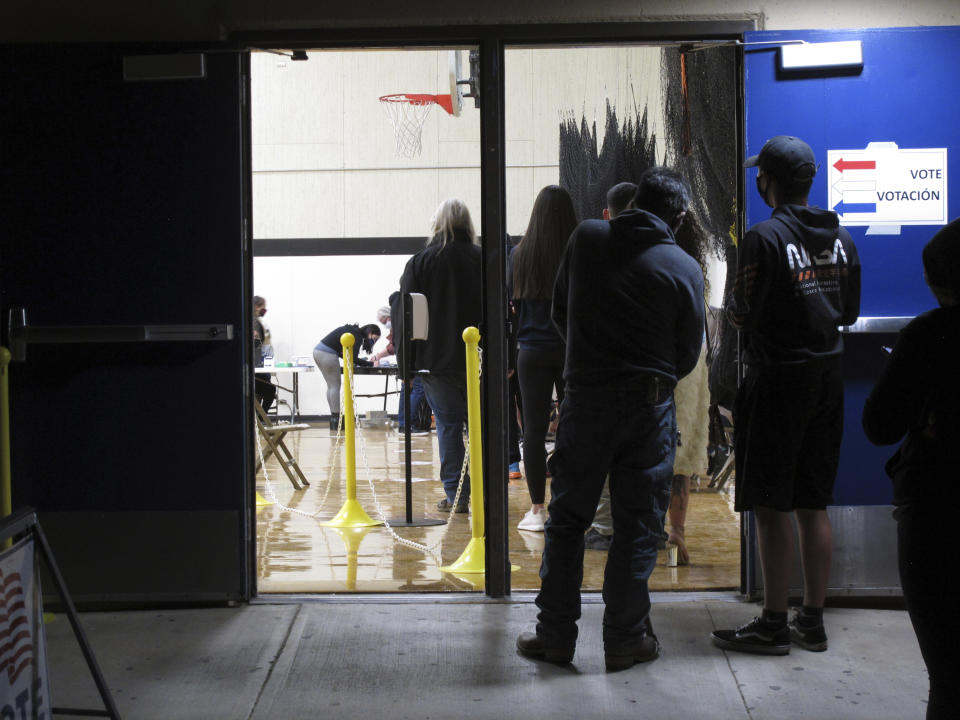 FILE - In this Nov. 3, 2020, file photo, some of the last voters wait in line to cast their ballots after the line was cut off at 7 p.m., local time, outside the gymnasium at Reed High School in Sparks, Nev. Everyone in line when the polls closed at 7 p.m. was allowed to vote in Washoe County, where registration is split evenly between the two major parties in the northern part of the state. A new survey measuring the popularity of major pieces of sweeping legislation in Congress finds solid support from Americans for Democrats’ proposals to overhaul voting in the U.S. The Associated Press-NORC Center for Public Affairs Research poll found about half of Americans support expanding access to early and mail voting, while about 3 in 10 opposed the ideas and the rest had no opinion. (AP Photo/Scott Sonner, File)