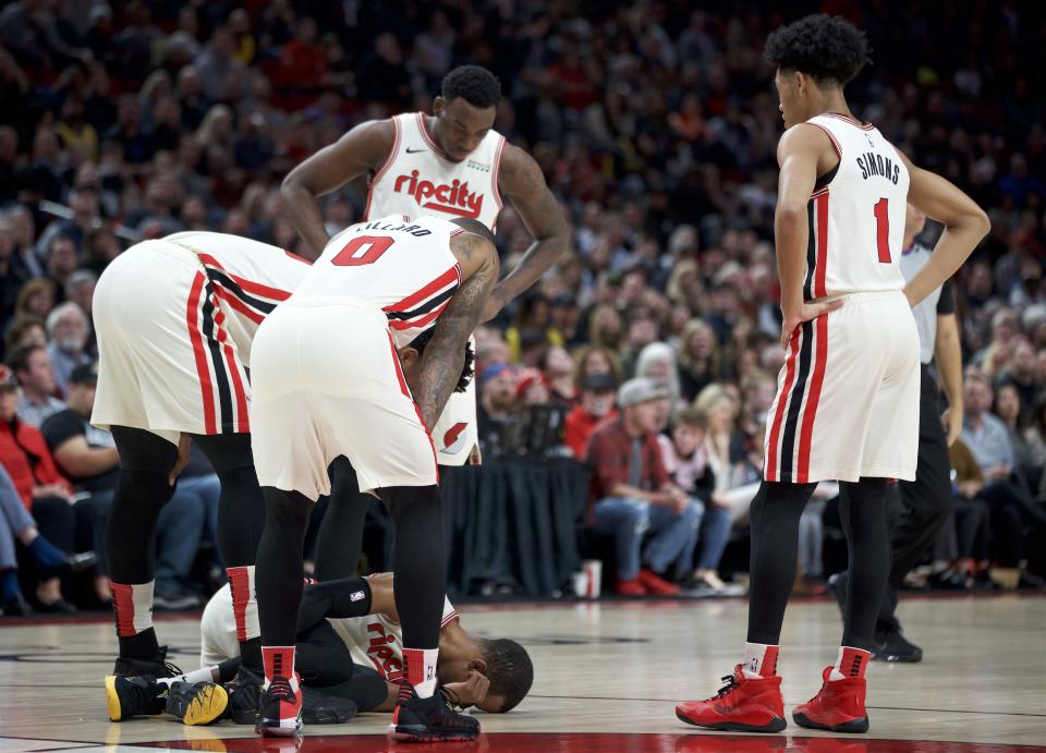 Portland Trail Blazers guard Rodney Hood is surrounded by teammates after tearing his Achilles tendon during the first half of the team's NBA basketball game against the Los Angeles Lakers in Portland, Ore., Friday, Dec. 6, 2019. (AP Photo/Craig Mitchelldyer)