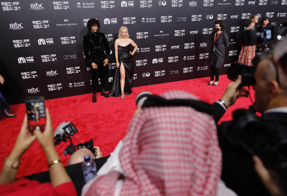 Russian Darja Pilz, Director of photography of the film, Sharaf, and Ahmed Al Munirawi, a Palestinian actor from Gaza, in the film, pose for photographers during the opening of the first edition of the Red Sea International Film Festival, in Jiddah, Saudi Arabia, late Monday, Dec. 6, 2021. Saudi Arabia is holding its first ever film festival three and-a-half years after the first movie premiered in cinemas in the kingdom. The festival featured a red carpet with women in floor-length ball gowns, a stark departure from past years when females had to wear the long flowing robe known as the abaya in public. (AP Photo/Amr Nabil)