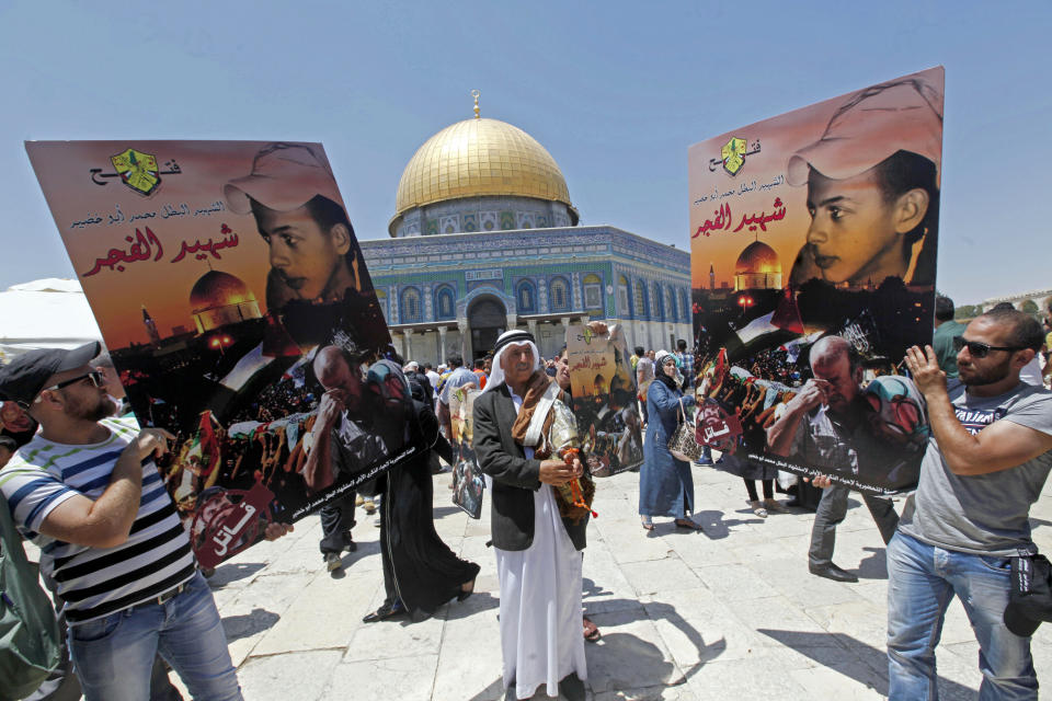 FILE -- In this July 3, 2015 file photo, Palestinians hold pictures of Mohammed Abu Khdeir, who was abducted and murdered by Israeli extremists in summer of 2014 in a revenge attack after Palestinian militants abducted and murdered three Israeli teenagers, as they protest next to the Dome of the Rock Mosque in the Al Aqsa Mosque compound, in Jerusalem's old city. HBO's new docudrama series, “Our Boys,” co-created by Palestinian and Israeli filmmakers, about the killings of four Israeli and Palestinian teenagers, which set off a cascade of events leading to the 2014 Gaza war, is set to air next week and is likely to reopen wounds on both sides of the conflict. Arabic on signs reads, "the martyr and hero Mohammed Abu Khdeir - The martyr of dawn." (AP Photo/Mahmoud Illean, File)