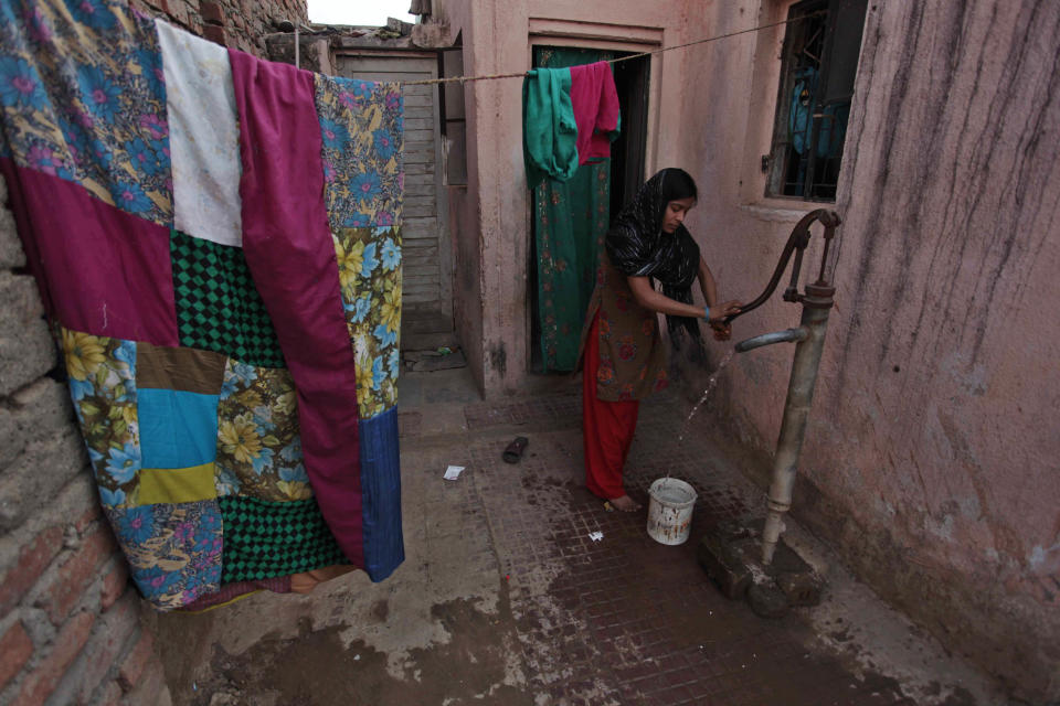 In this March 27, 2014 photo, an Indian Muslim woman collects water from a hand pump at her home at Fatewadi area in Ahmadabad, Gujarat state, India. As India, Asia's third-largest economy, holds elections that will gauge the mood of millions of new voters, Narendra Modi's Hindu nationalist party is proclaiming the economic success of Gujarat. Bharatiya Janata Party faithful say the state's record shows how to re-energize India's sputtering growth, get much needed infrastructure back on track and streamline the tangled bureaucracy that scares away investment.(AP Photo/Ajit Solanki)