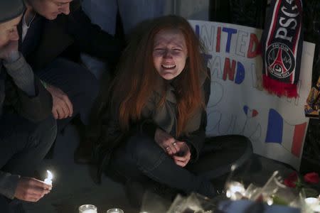 Polina Volkova, a friend of Eagles Of Death Metal Nick Alexander who died in attacks in Paris, cries as she sits near a makeshift vigil outside the consulate of France in the Manhattan borough of New York November 14, 2015. REUTERS/Carlo Allegri