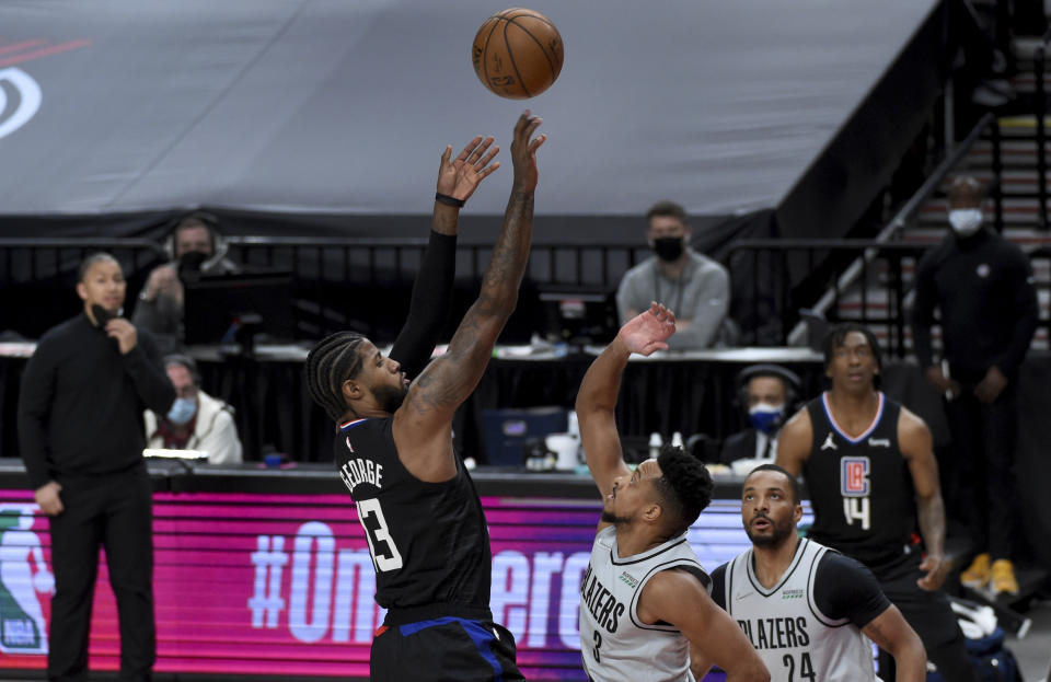 Los Angeles Clippers guard Paul George, left, hits a shot over Portland Trail Blazers guard CJ McCollum, right, during the first half of an NBA basketball game in Portland, Ore., Tuesday, April 20, 2021. (AP Photo/Steve Dykes)