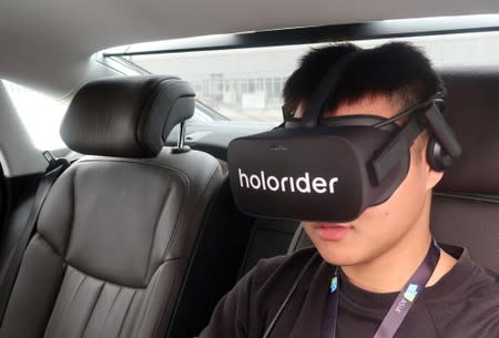 Staff member wears Holoride VR goggles inside an Audi vehicle during a demonstration at the CES Asia exhibition in Shanghai