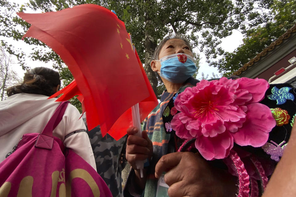 A vendor selling Chinese flags waits near tourists lining up for security checks to enter the Tiananmen area during National Day in Beijing on Thursday, Oct. 1, 2020. Millions of Chinese tourists usually would use their week-long National Day holidays to travel abroad. This year, travel restrictions due to the coronavirus pandemic mean that some 600 million tourists - about 40% of the population - will travel within China during the holiday that began Thursday, according to Ctrip, China's largest online travel agency. (AP Photo/Ng Han Guan)