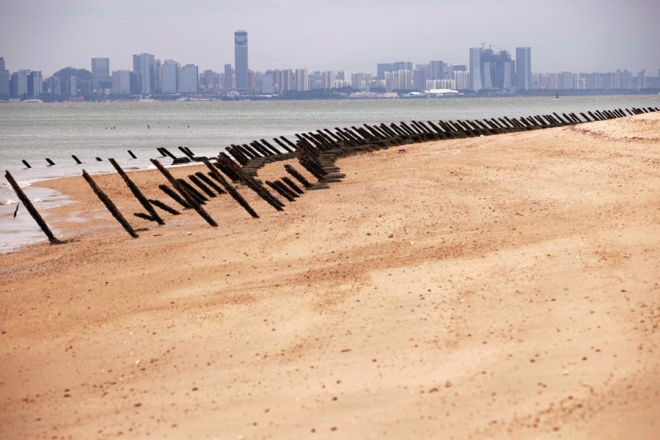 As the city of Xiamen, China, is seen in the background, wartime anti-tank obstacles sit on a beach on 7 October 2023 in Kinmen (Getty Images)